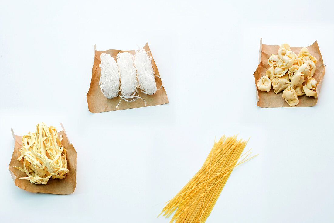 Asian noodles, fettuccine, tortellini and spaghetti on brown paper