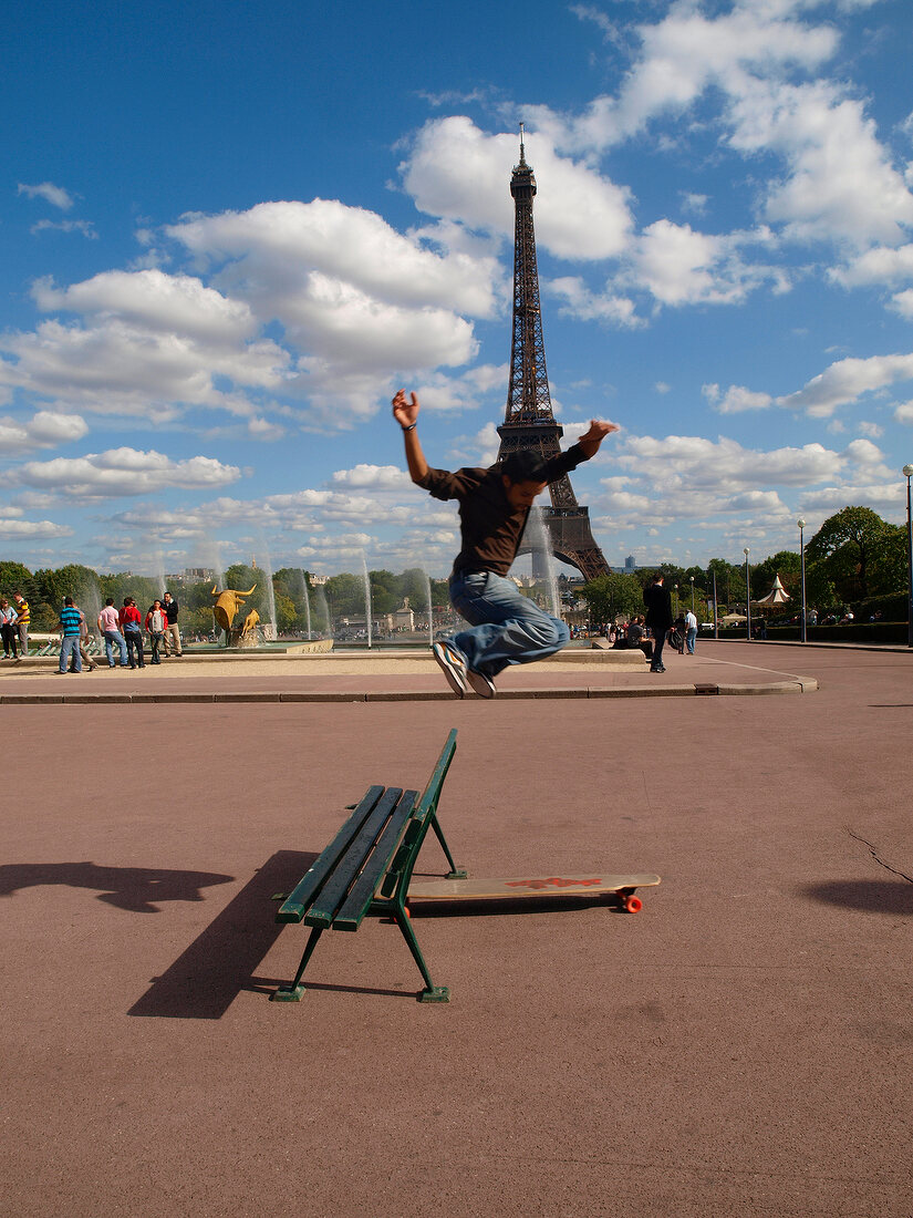 Man jumping on long skateboard in front of Eiffel Tower, Paris