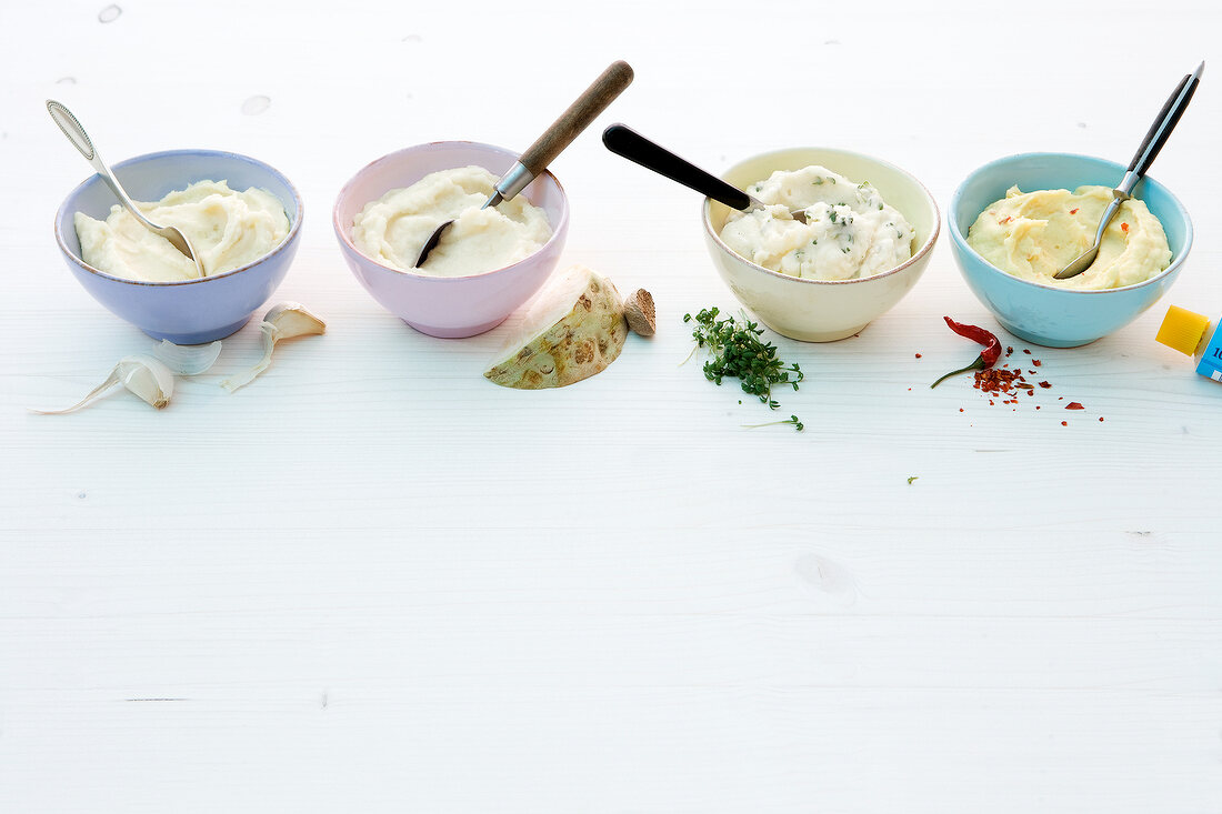 Four different dishes of mashed potatoes in bowls