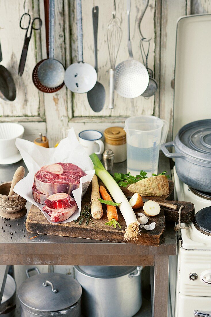 Ingredients for beef broth on a kitchen work surface next to a stove in a country house-style kitchen