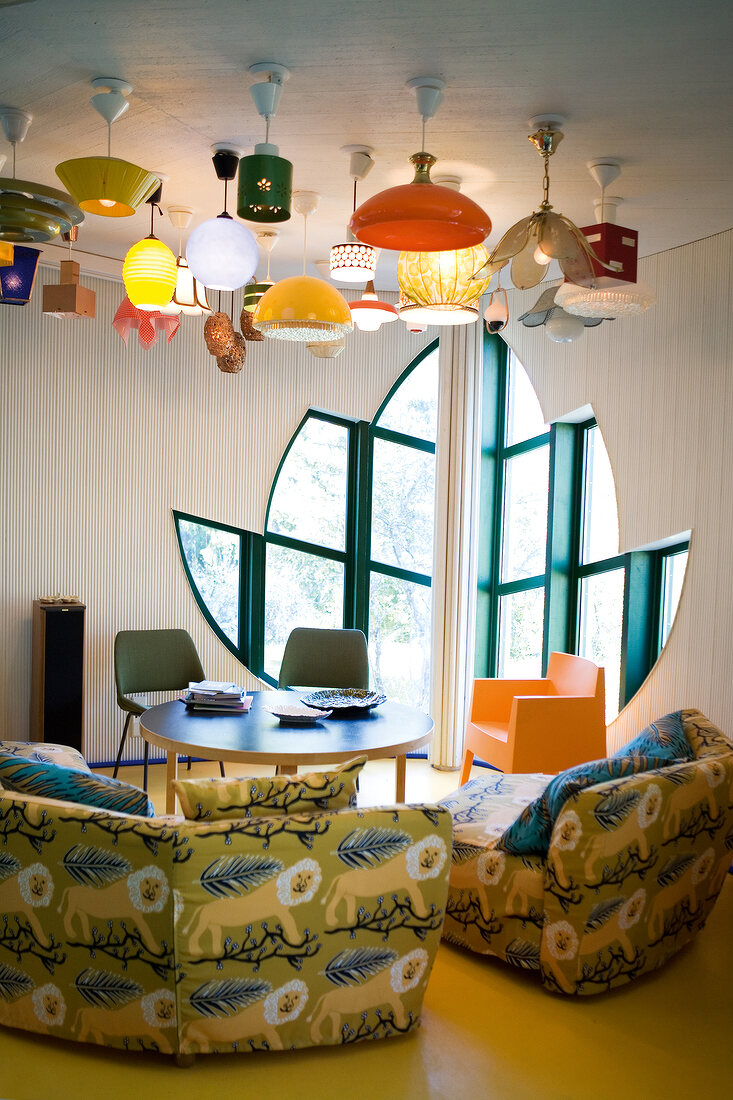 Modern room with flower shaped window, animal print sofas and various lamps on ceiling