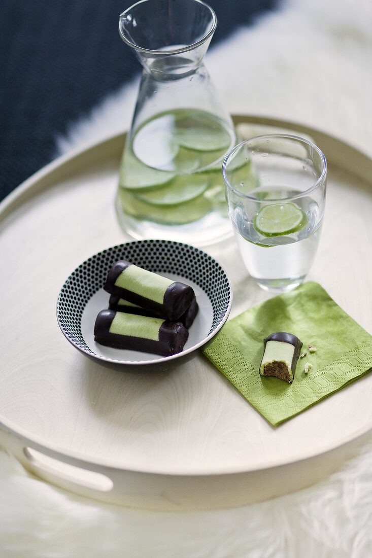 Chocolates in bowl and napkin, water and lime slices in pitcher and glass
