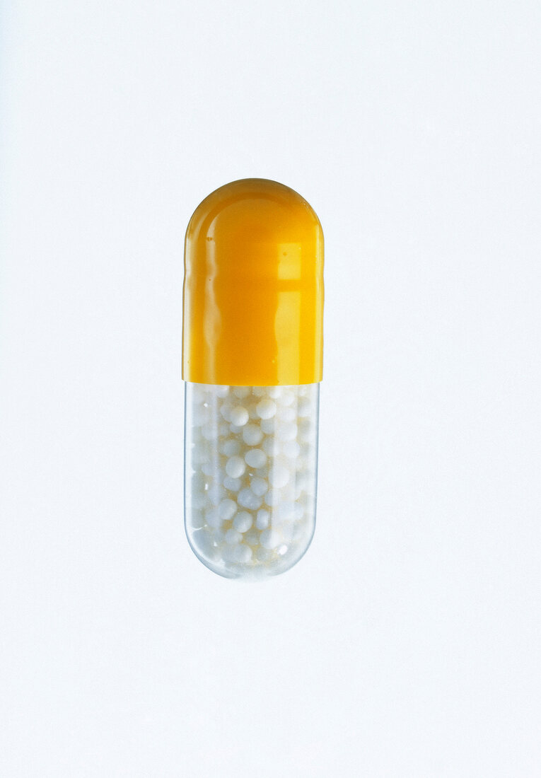 Cut out of yellow and white capsule against white background, close-up