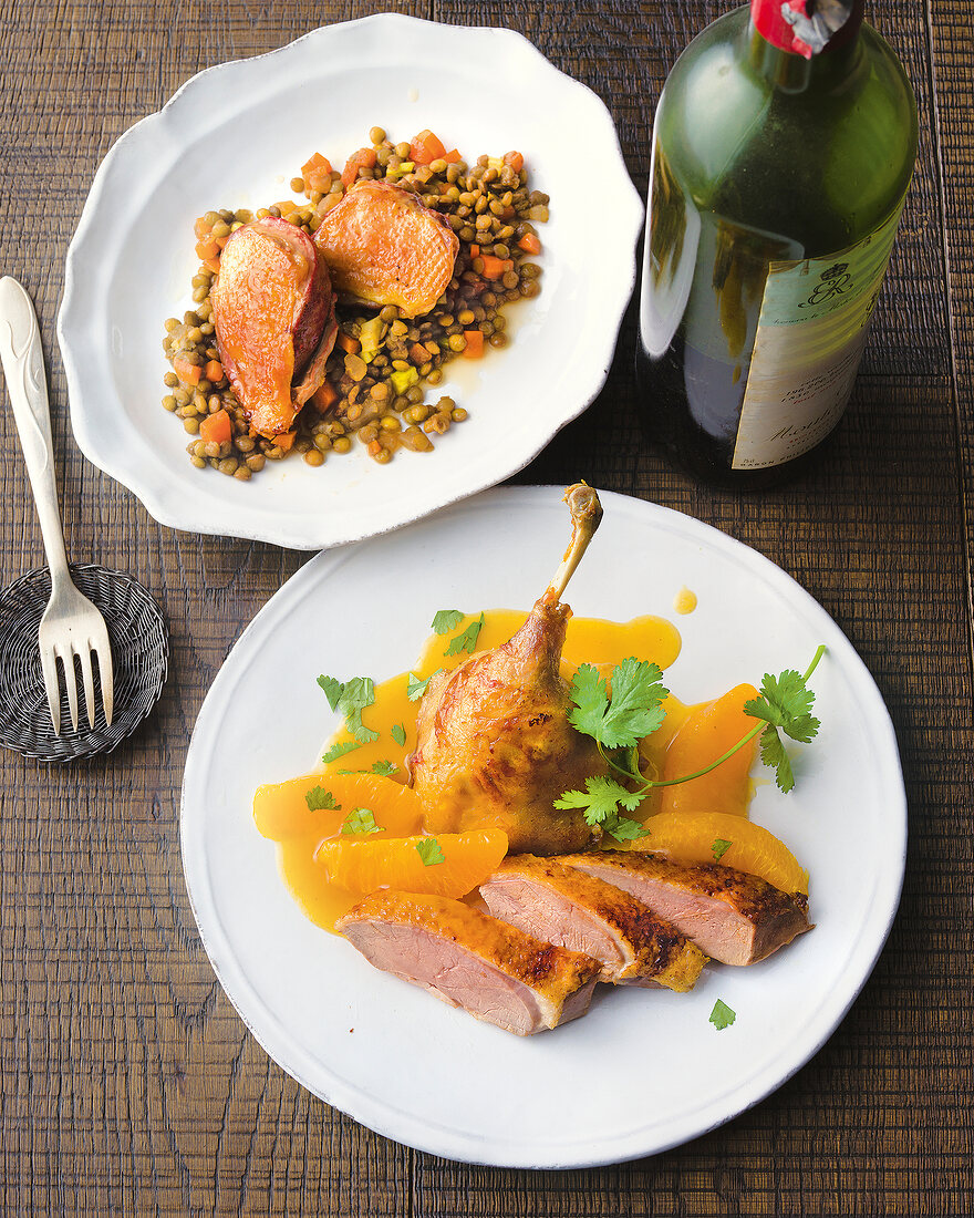 Fried pigeon breast on lentils and duck with orange sauce on plate