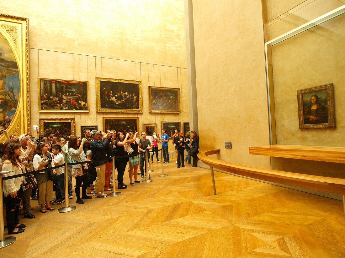 Tourists photographing Mona Lisa painting at Louvre Museum in Paris, France