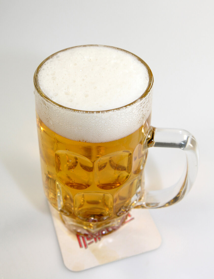 Beer with foam in beer mug on white background, close-up