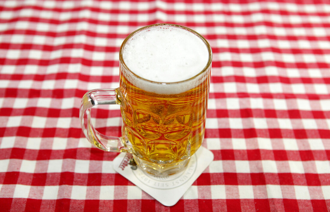 Glass of beer on red and white checked table cloth