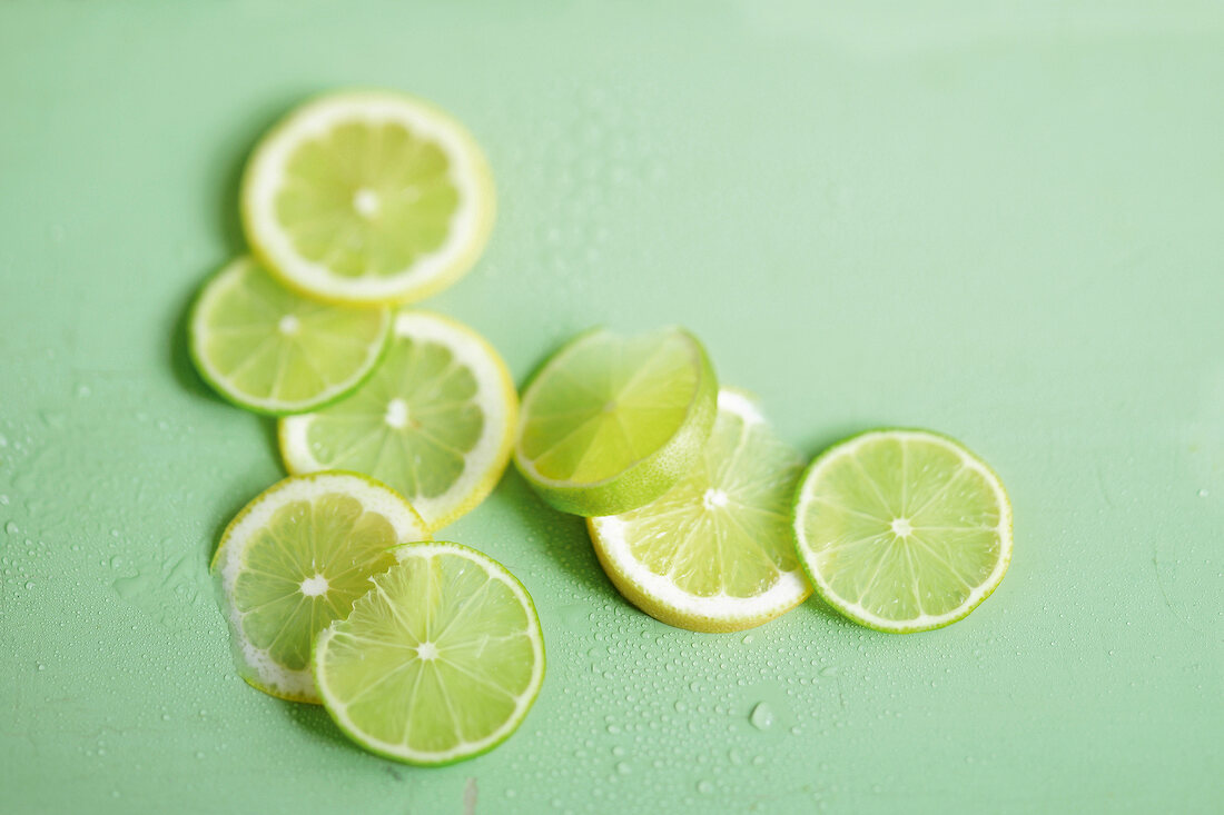 Close-up of lime and lemon slices on green background