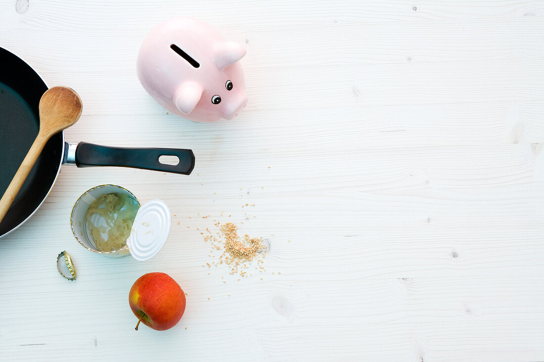 Frying pan, piggy bank, apple and open can on white background
