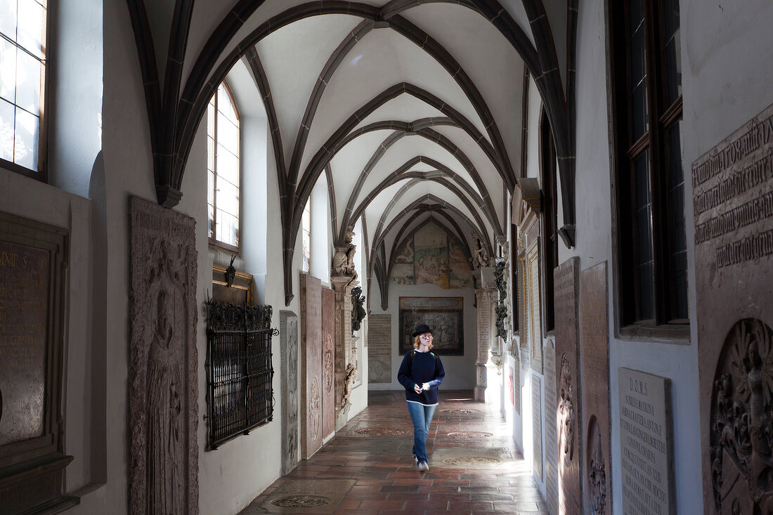 Woman walking in cloister at St. Anne's Church, Augsburg, Bavaria, Germany