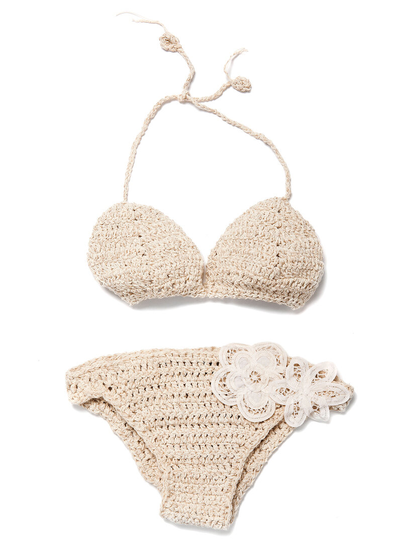 Close-up of beige crochet bikini with floral lace on white background