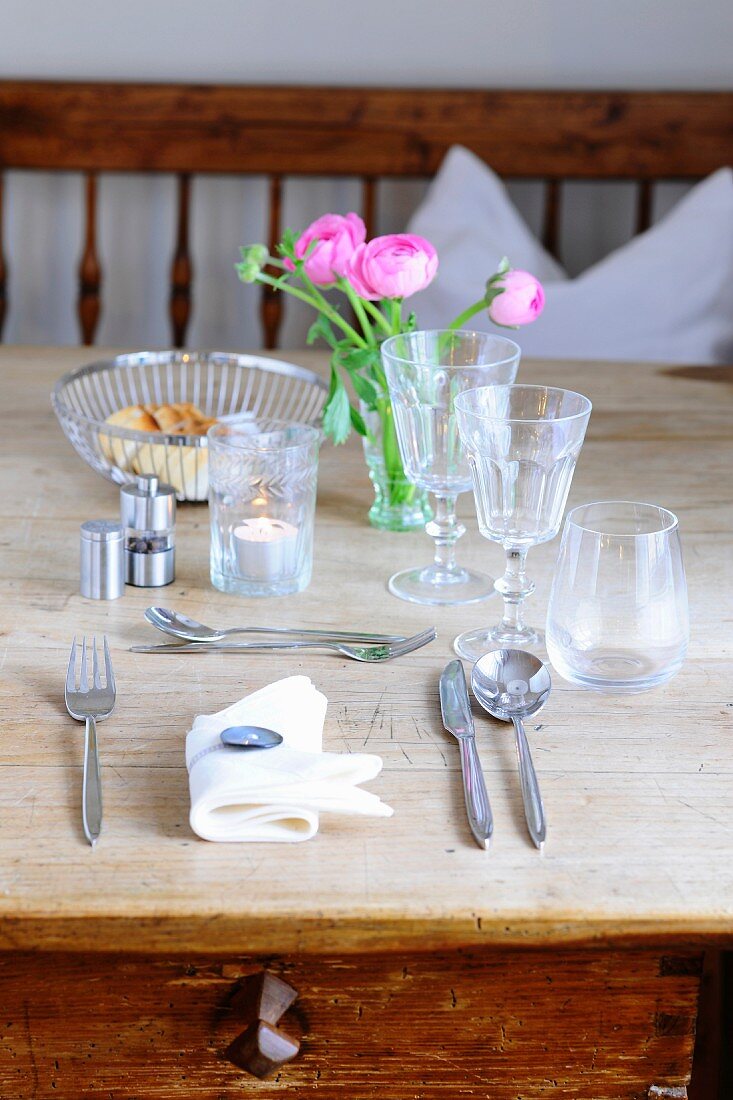 A place setting with cutlery and glasses on a rustic wooden table