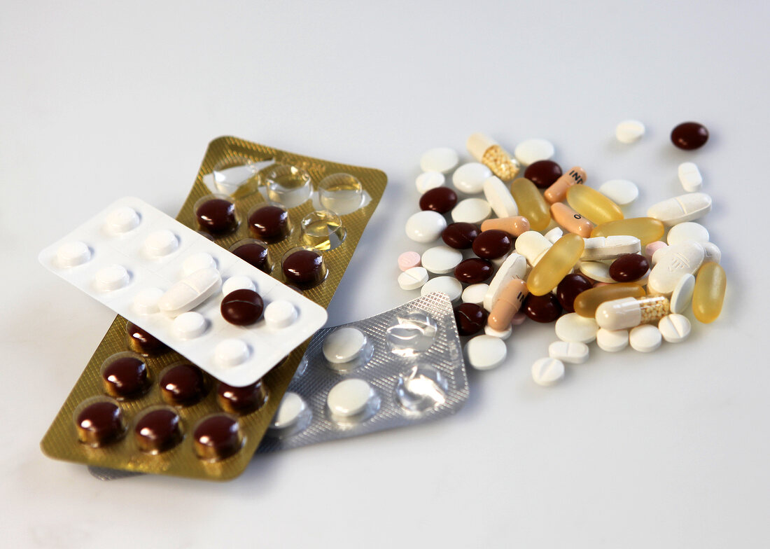 Multi-coloured tablets, capsules and push-through strips of medicines on white background