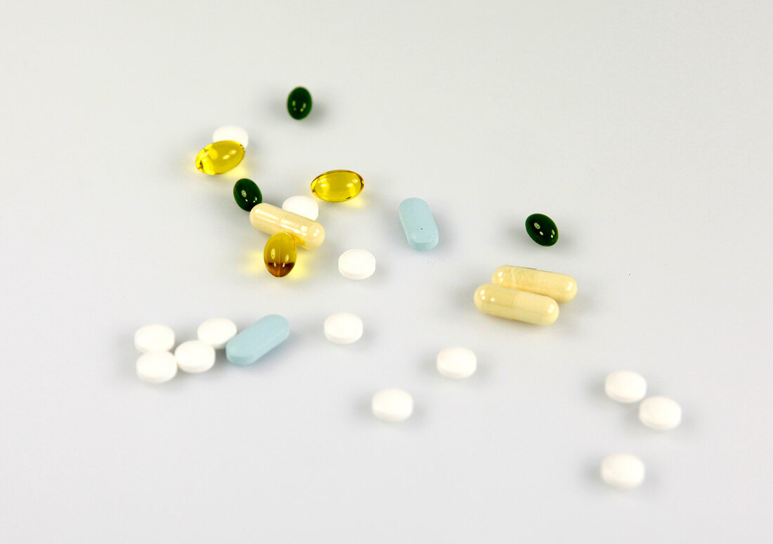 Multi-coloured tablets and capsules on white background
