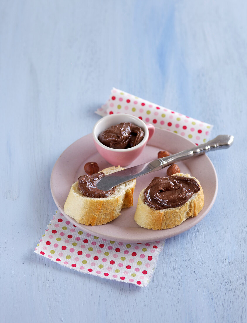 Chocolate nut spread on slices of bread and in small cup