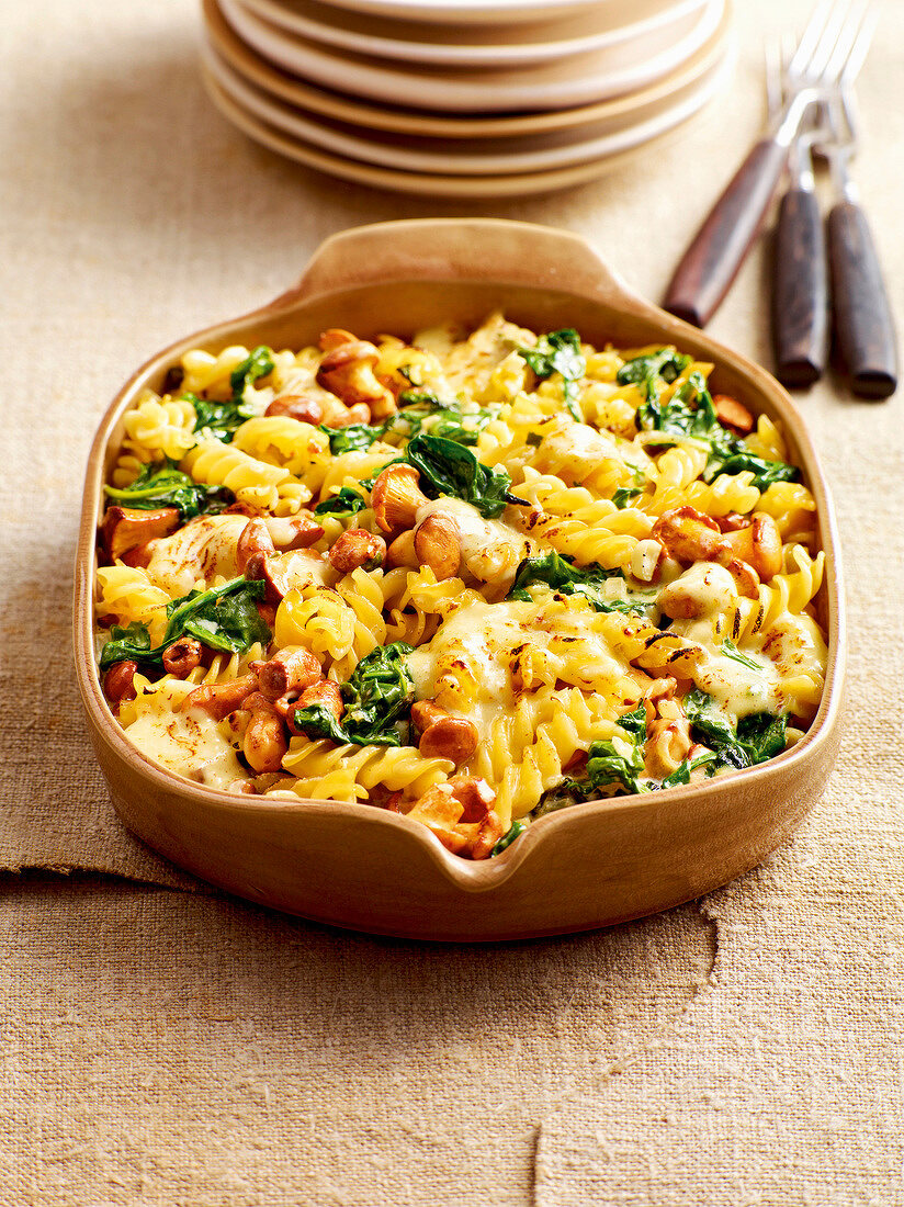 Baked pasta with spinach and chanterelles in baking pan