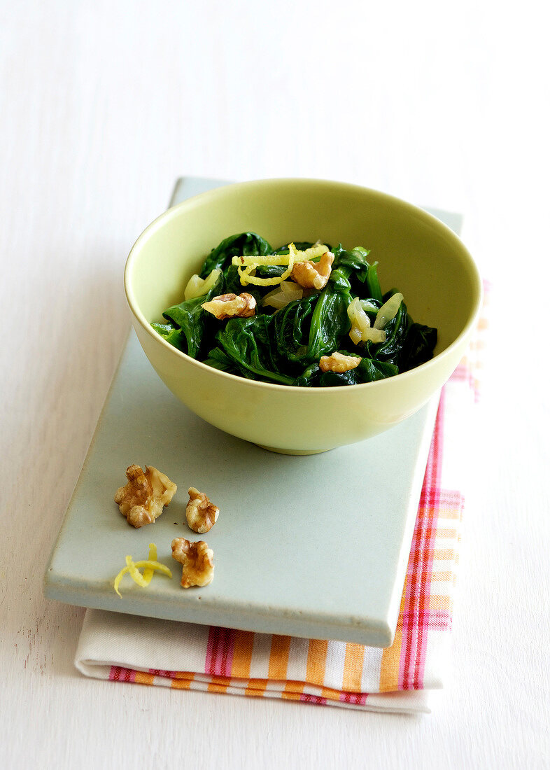 Lemon spinach with walnuts in bowl