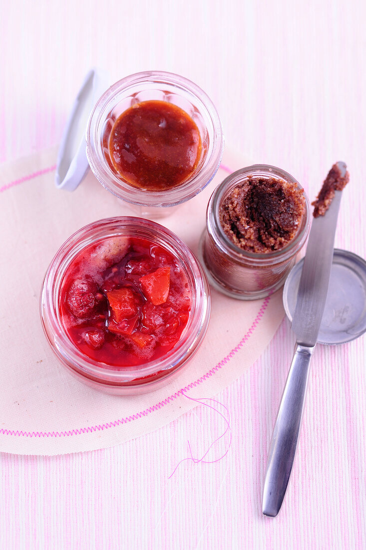 Three glass jars with plum jam, nectarines with raspberry jam and nut butter