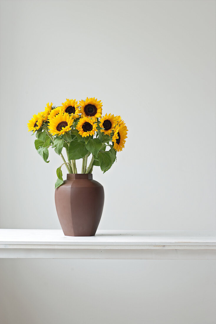Vase with sunflowers on white table