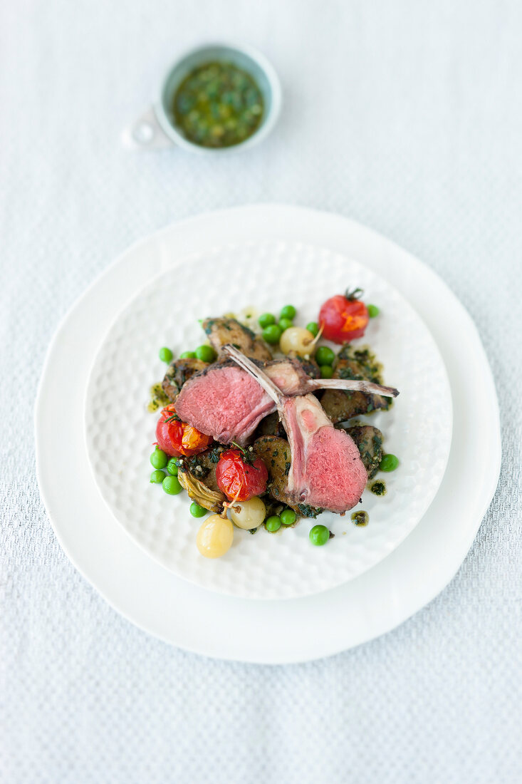 Rack of lamb with vegetables and olive pesto on plate