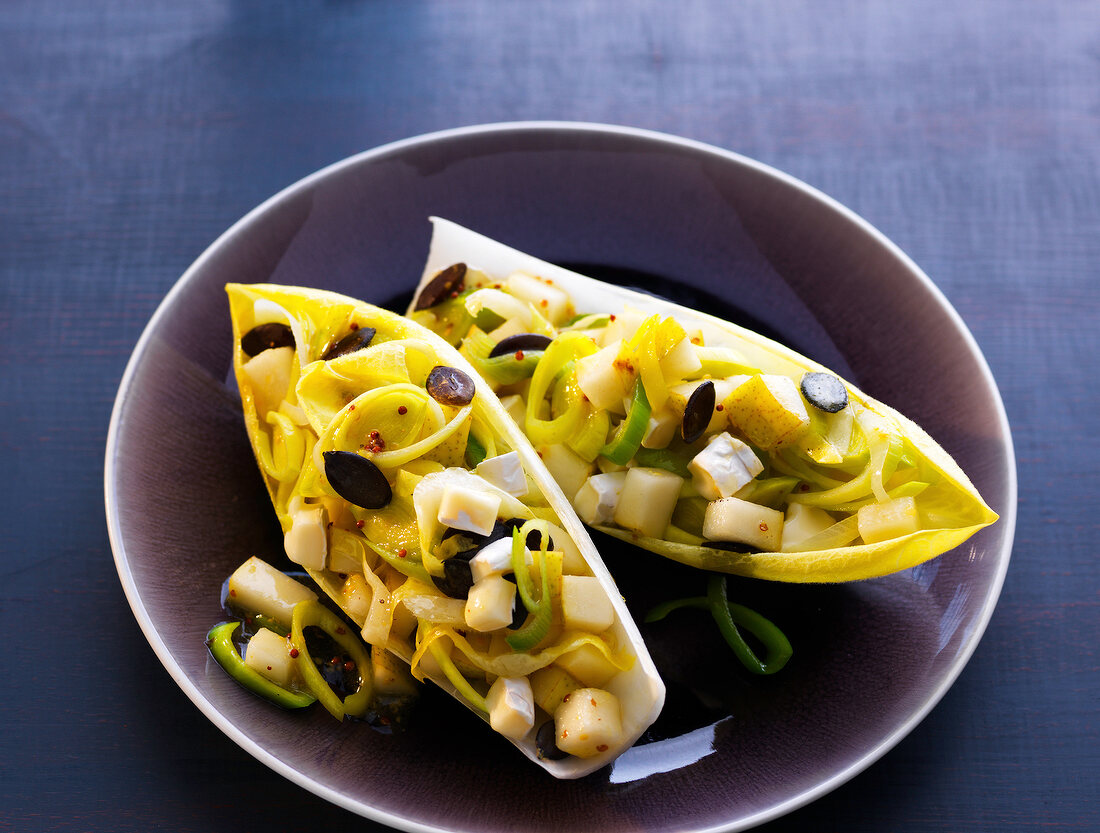 Chicory boats stuffed with vegetables and pear on plate