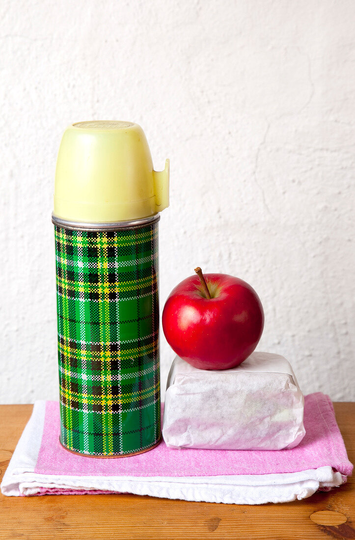 Thermos, apple green and bread wrapped in paper