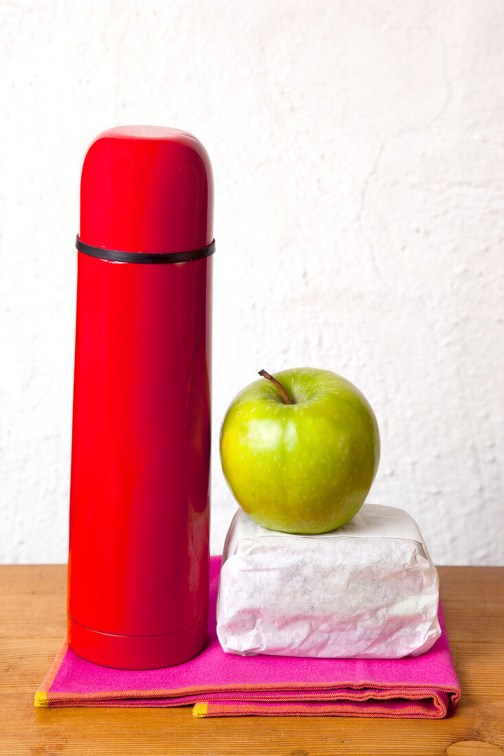 Thermos, apple green and bread wrapped in paper