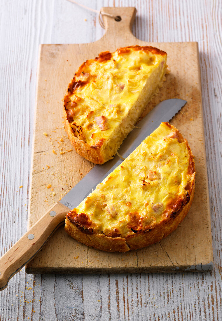 Halved and baked herb quiche with apple and munster cheese on chopping board