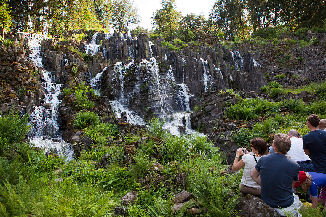 Tourists near waterfall in mountain park, Kassel, Hesse, Germany