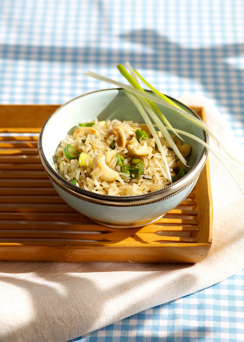 Cashew nut and onion rice in bowl on wooden tray