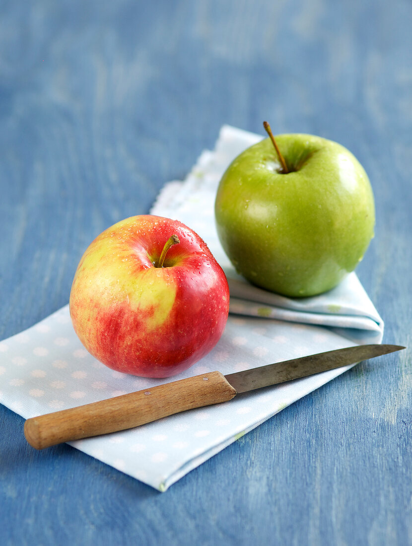 Red apple and green apple with knife on napkin