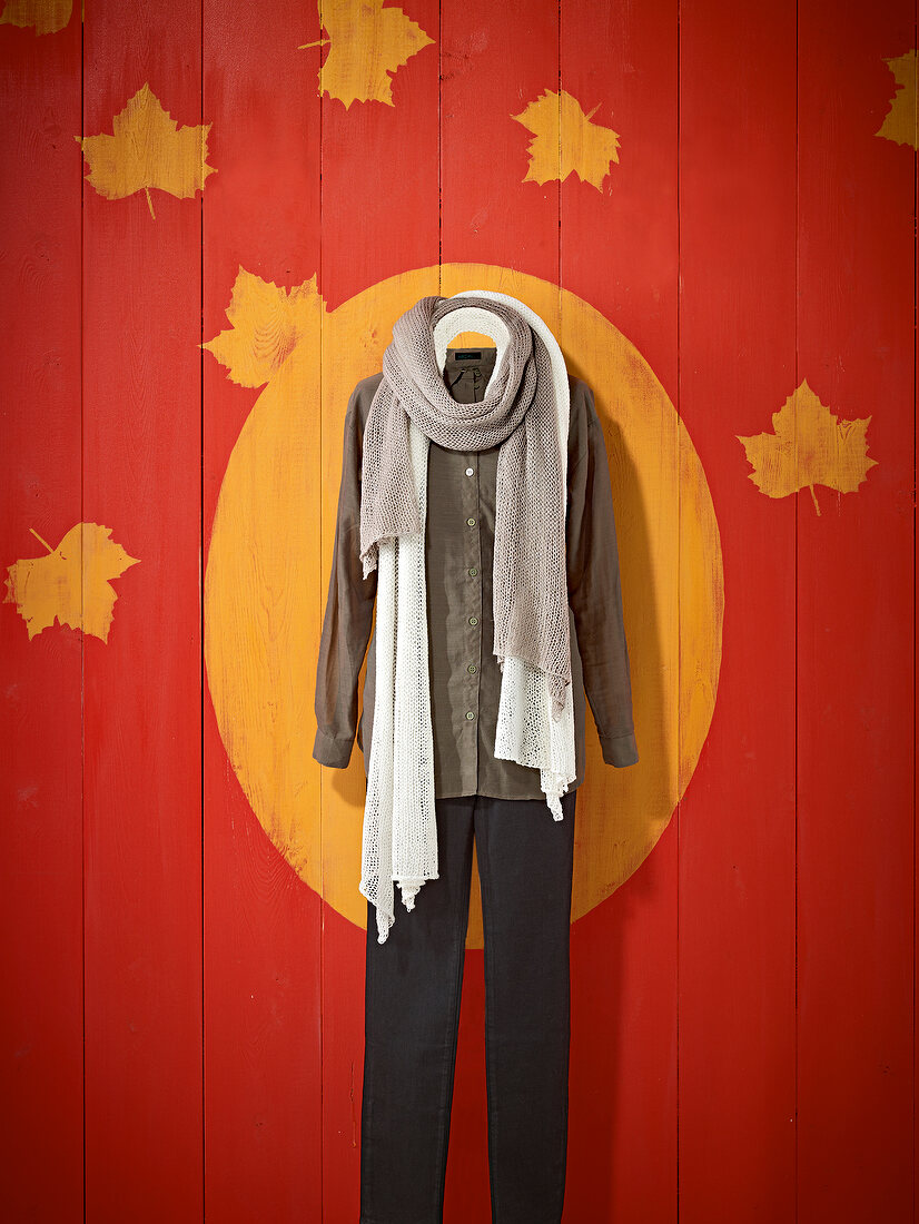 Brown shirt with black pants, white and beige lace scarf against patterned wall