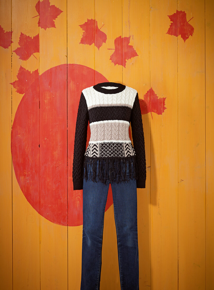 Jacquard pattern sweater with blue jeans on patterned wall
