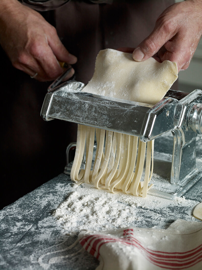 Close-up of dough being put through pasta maker while preparing pasta, step 3
