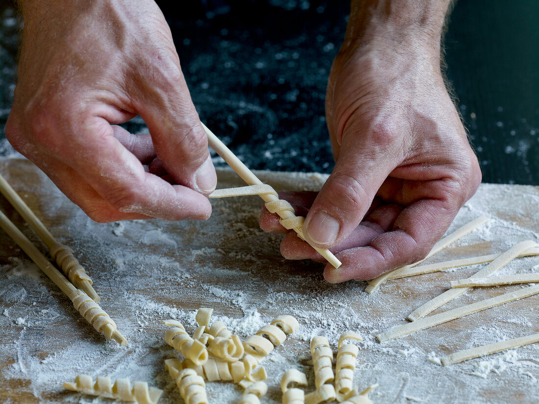 Close-up of dough rolled around stick while preparing fusilli pasta