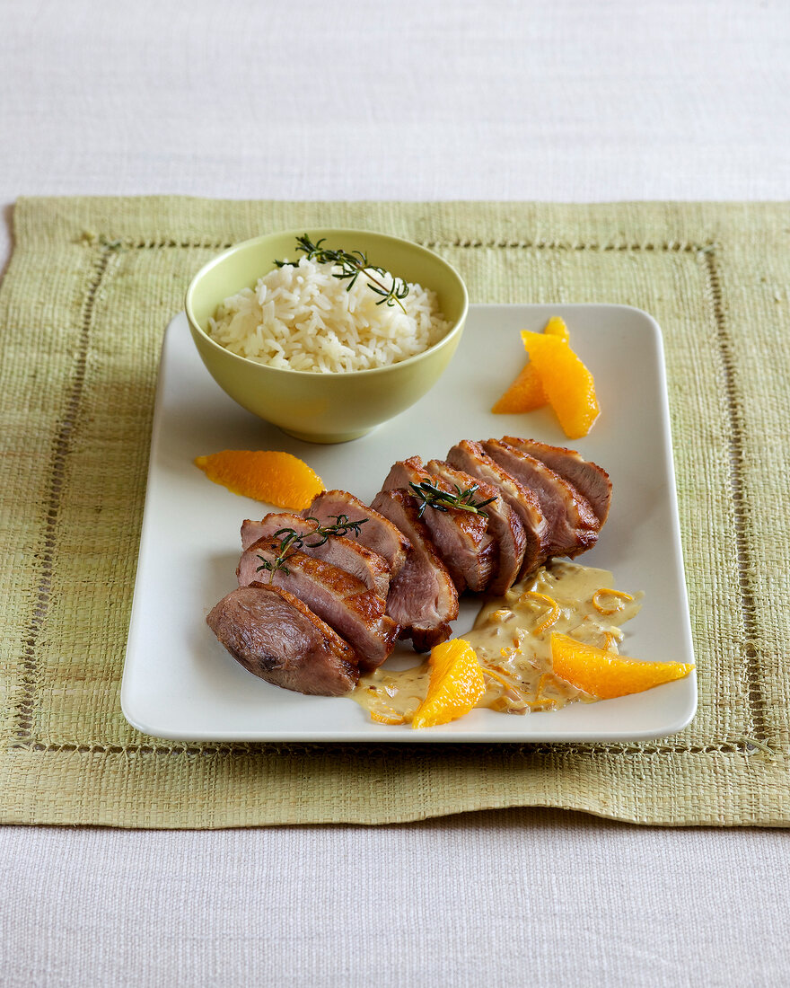 Duck breast with orange sauce and rice in serving plate