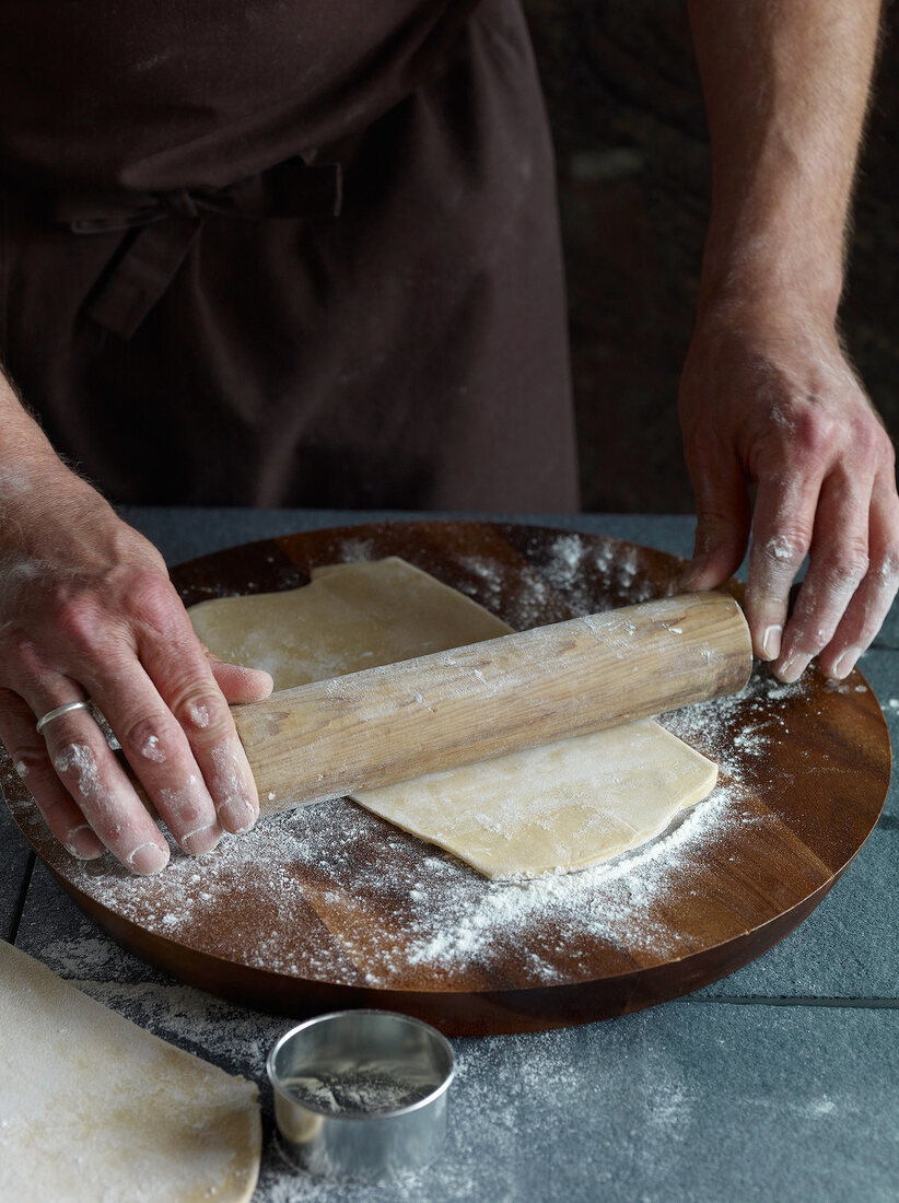 Dough being rolled with rolling pin for preparation of tortellini pasta, step 1