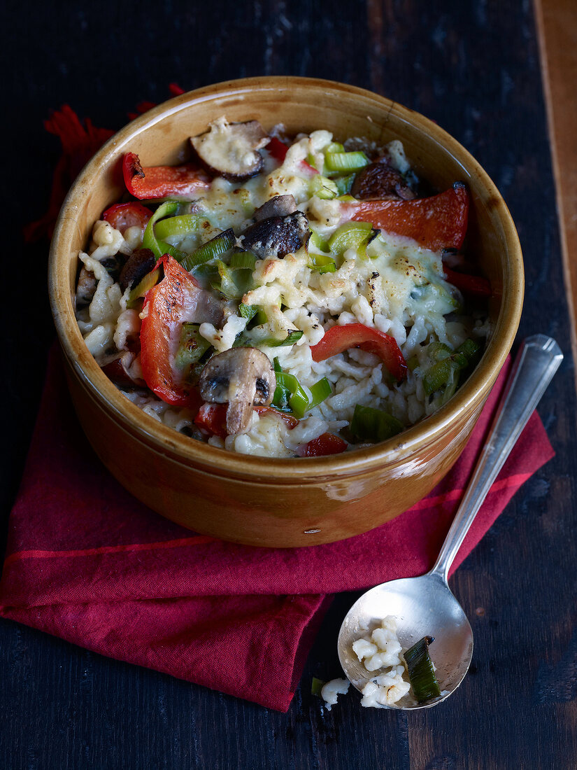 Spaetzle gratin with mushrooms and vegetables in clay pot
