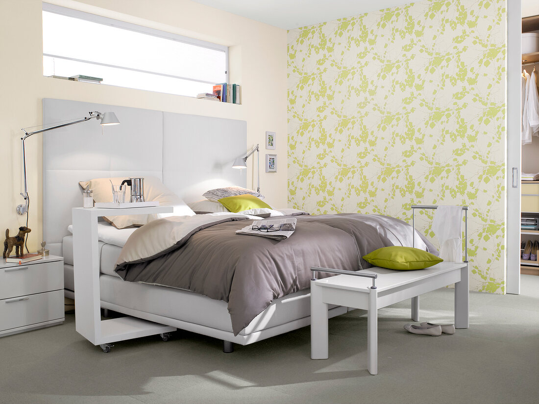 Bedroom with double bed beside white and green patterned wall