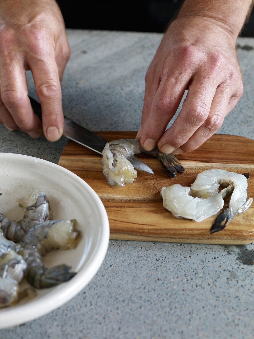 Close-up of shrimp being cut for preparing shrimp in garlic tomato sauce, step 3