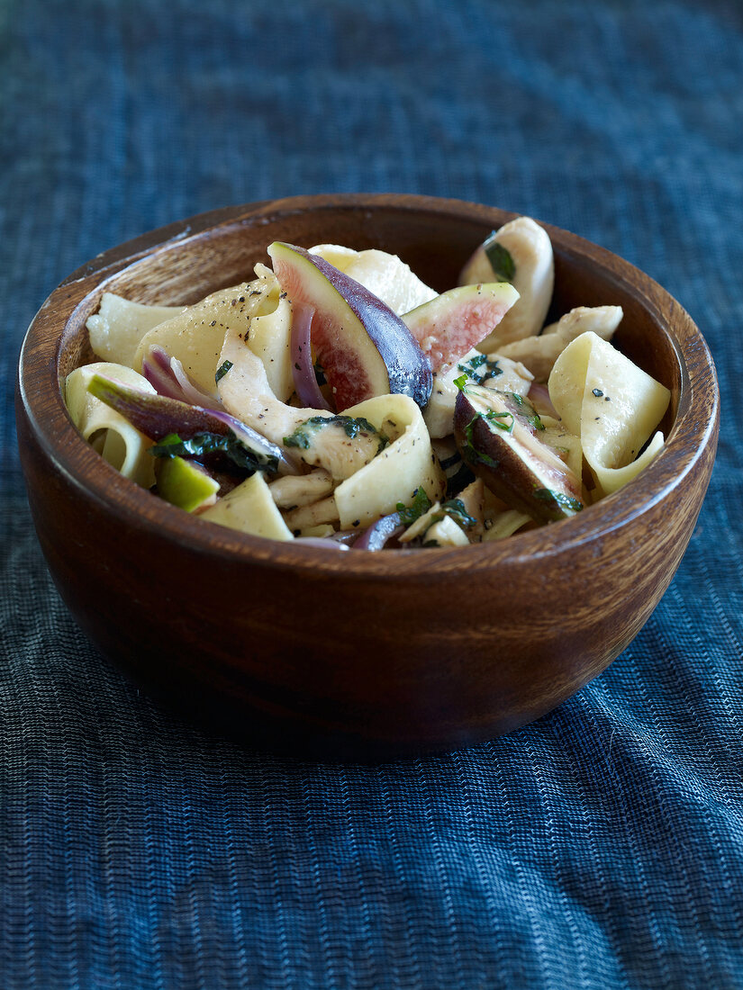 Chicken strips with figs in wooden bowl