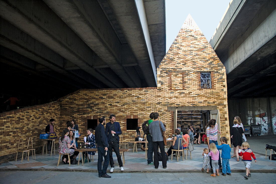 People in house under bridge, East End, London, UK