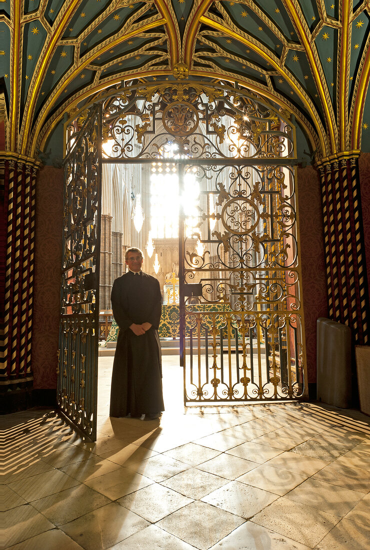 Clergyman standing on gate of Westminster Abbey, London, UK