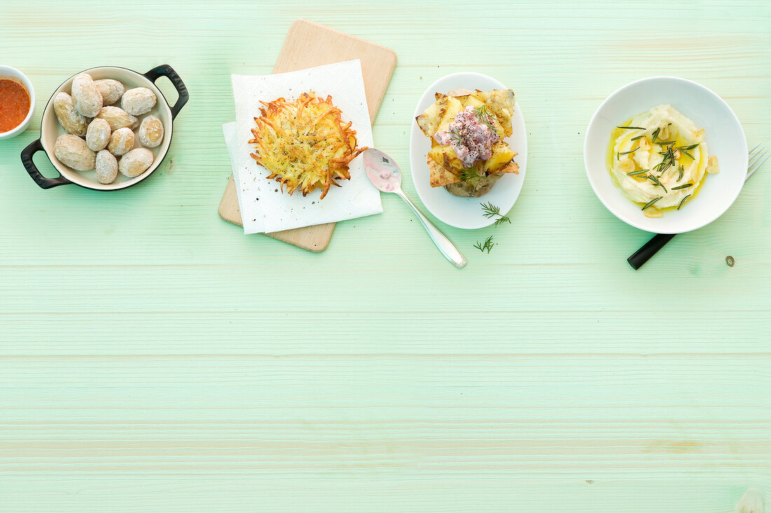 Various potato dishes on plates, pan and wooden board