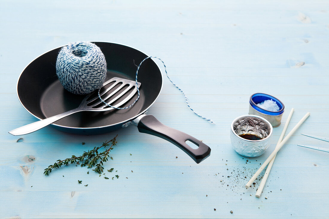 Frying pan, string, spatula and chopsticks on blue background