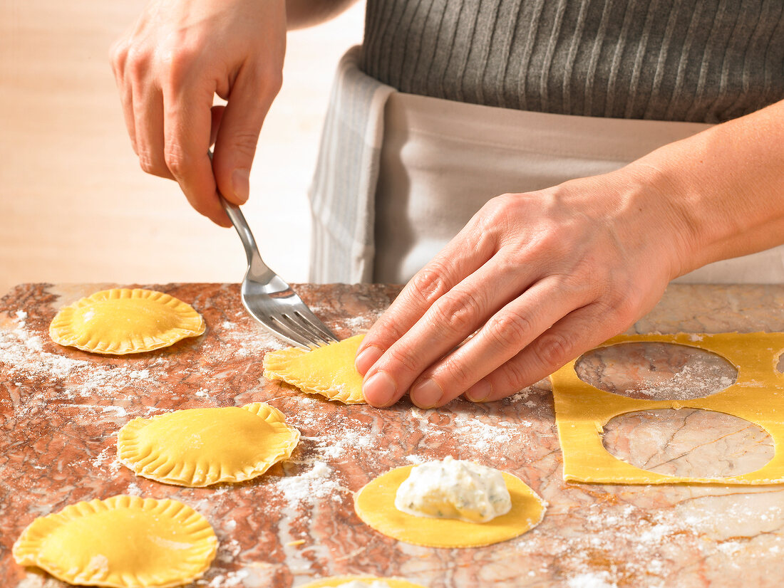 Close-up of hand filling ravioli and pricking it with fork