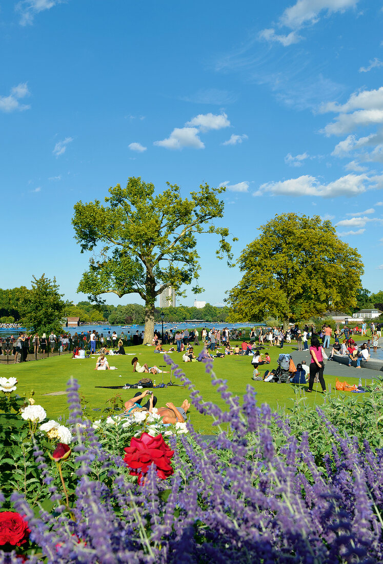People relaxing in Hyde Park near Serpentine lake, London, UK