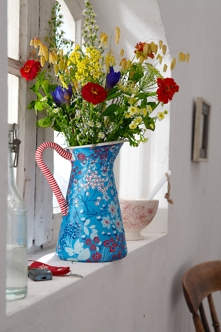 Close-up of blue vase with bouquet on window sill