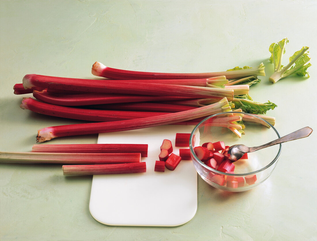 Whole and sliced rhubarb on chopping board and bowl