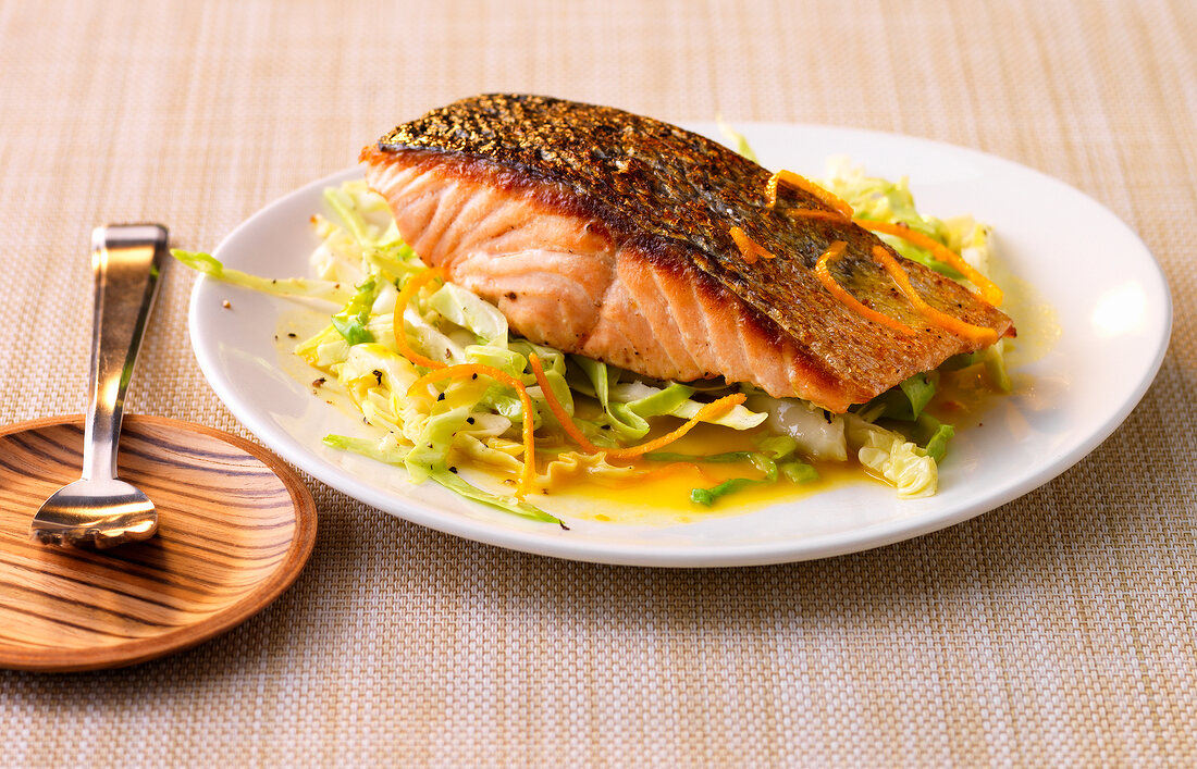 Salmon with cabbage and oranges on plate